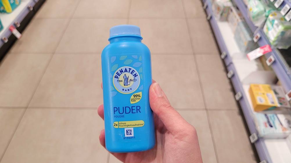 Eine Hand hält den Babypuder im Test hoch.