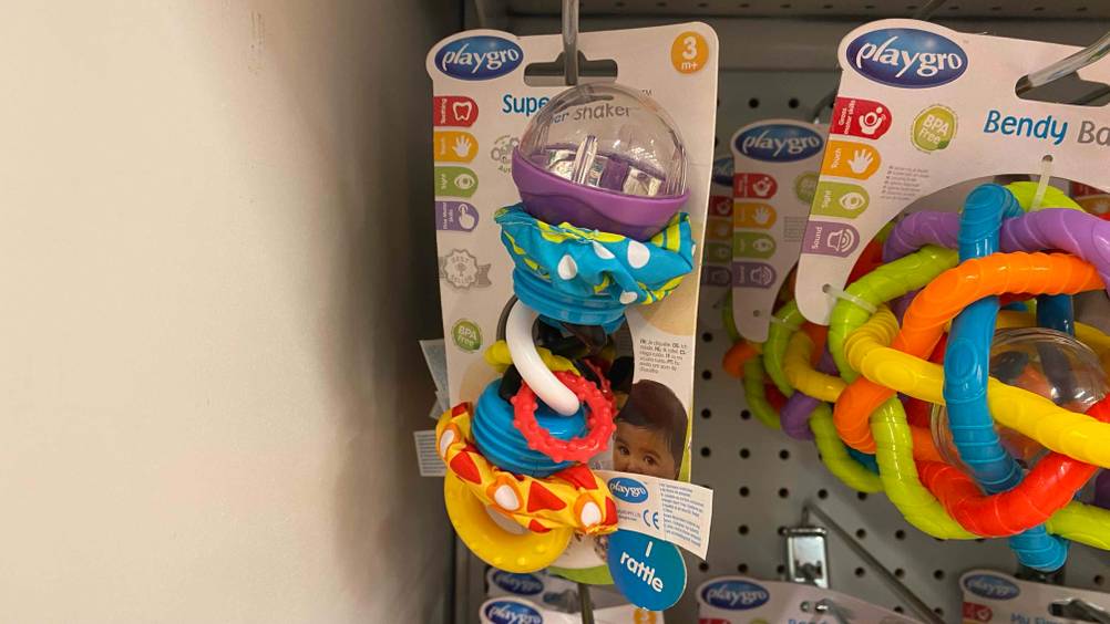 Eine Babyrassel im Test: in einem Kaufhaus hängt eine verpackte Babyrassel.