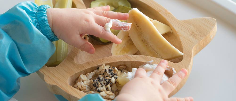 Kind isst vom Babyteller mit Saugnapf.