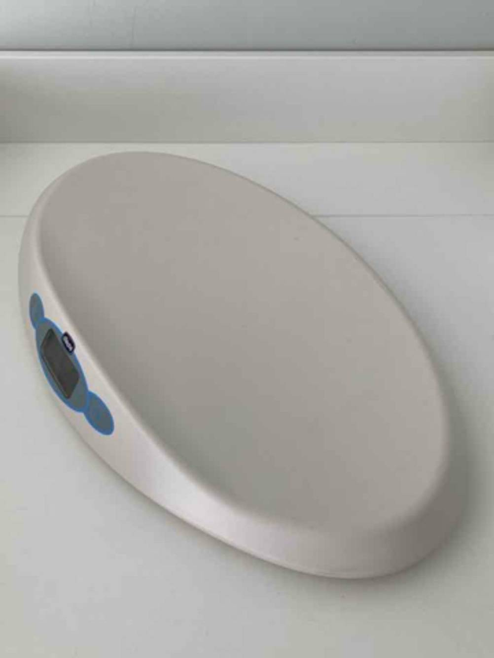 Ansicht der flachen, weißen Babywaage im Test, mit seitlichen Programmiertasten und Display, von oben betrachtet.