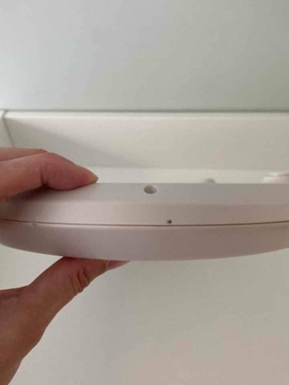 Eine Hand hält die weiße Babywaage im Test vor einem weißen Hintergrund.