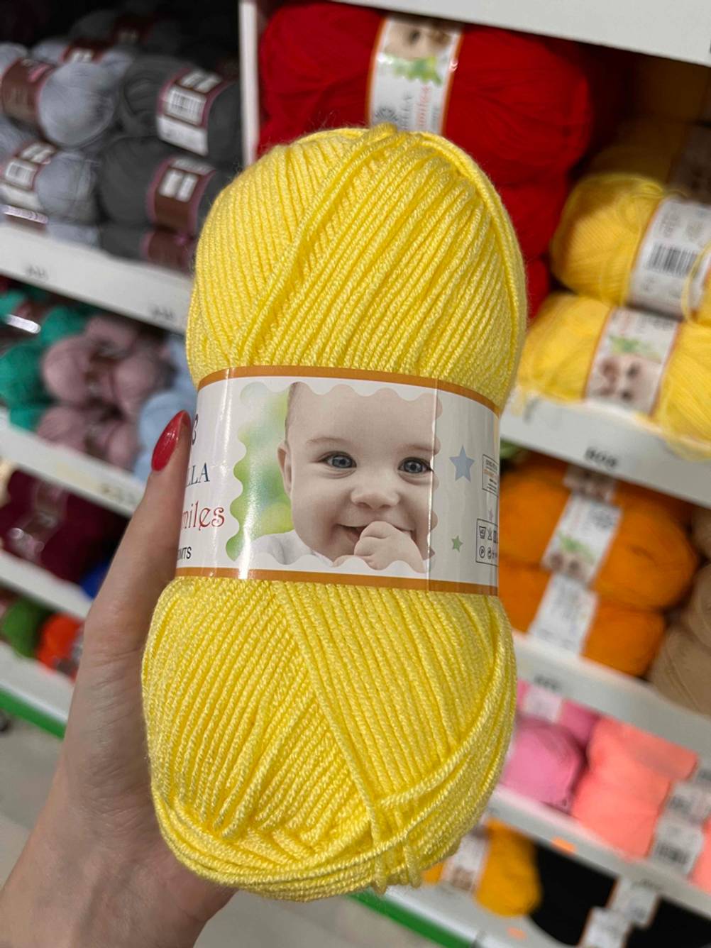 Babywolle im Test: In der Hand befindet sich ein gelbes Wollknäuel. 