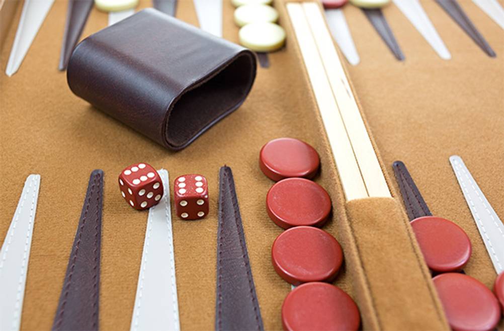 Backgammon-Koffer im Test: Ein Backgammon-Spielfeld aus Filz auf dem Würfelbecher, Würfel und Spielsteine zu sehen sind.