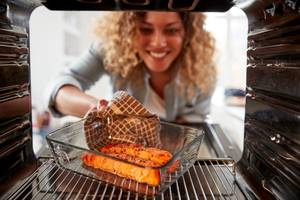 Backofenrost im Test: Frau gibt Auflauf in Backofen