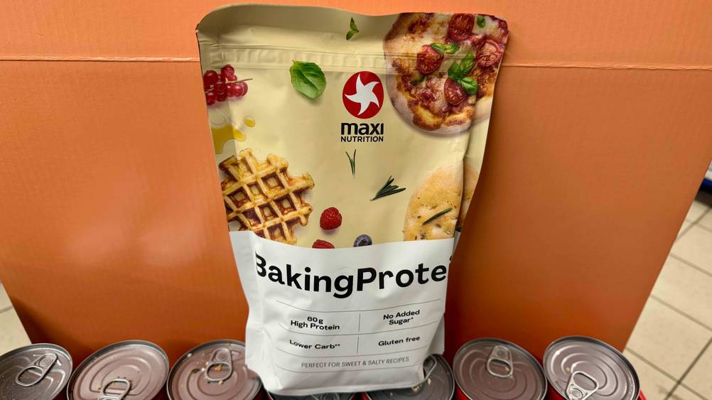 Vor einer orangen Fläche steht das Backprotein im Test auf mehreren Dosen.
