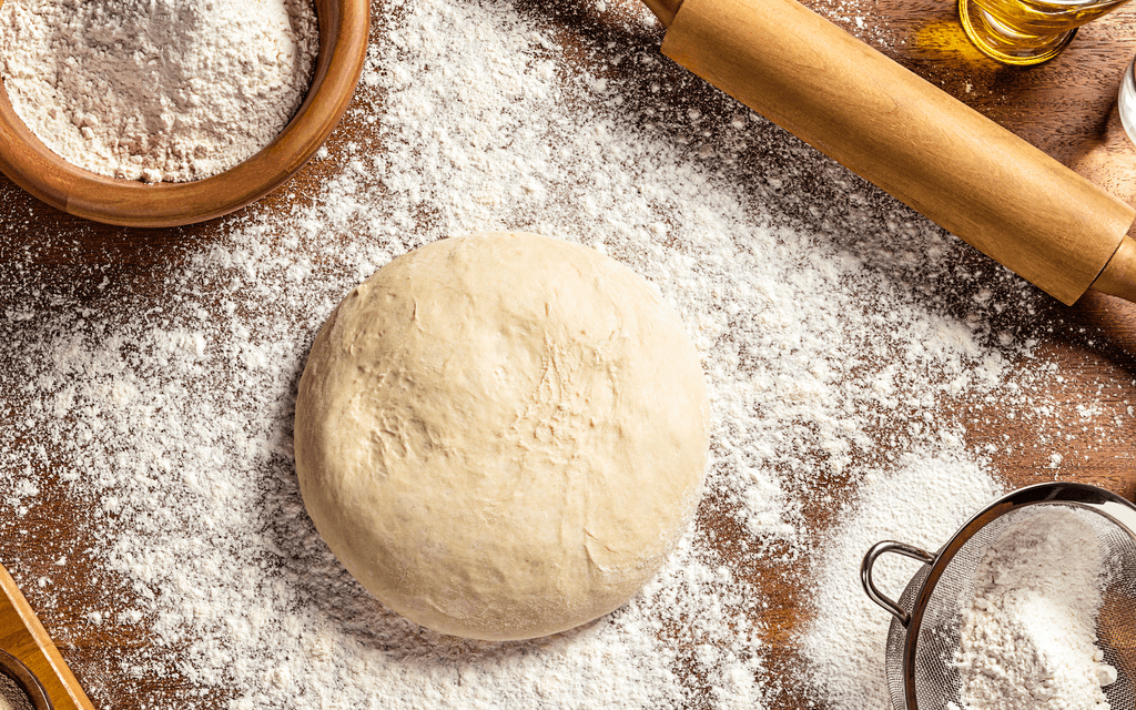 Backprotein-Test: Ein Pizzateig auf einem Holzbrett. 