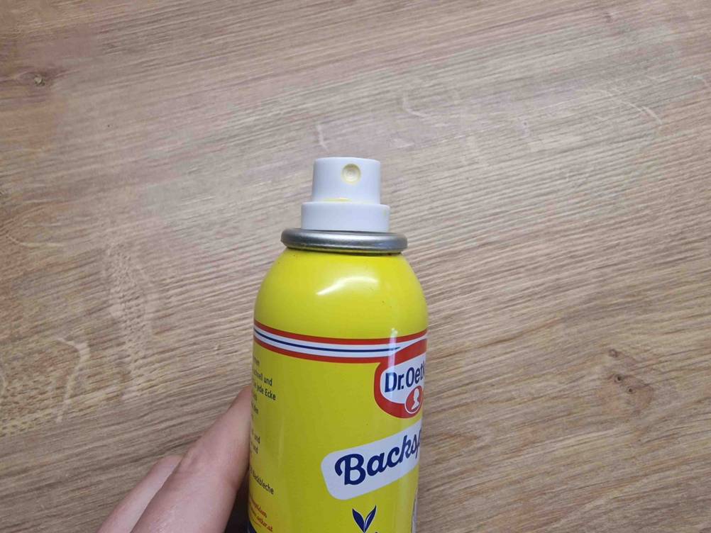 Nahaufnahme des Sprühkopfes eines Backtrennsprays vor einer Holzfläche.