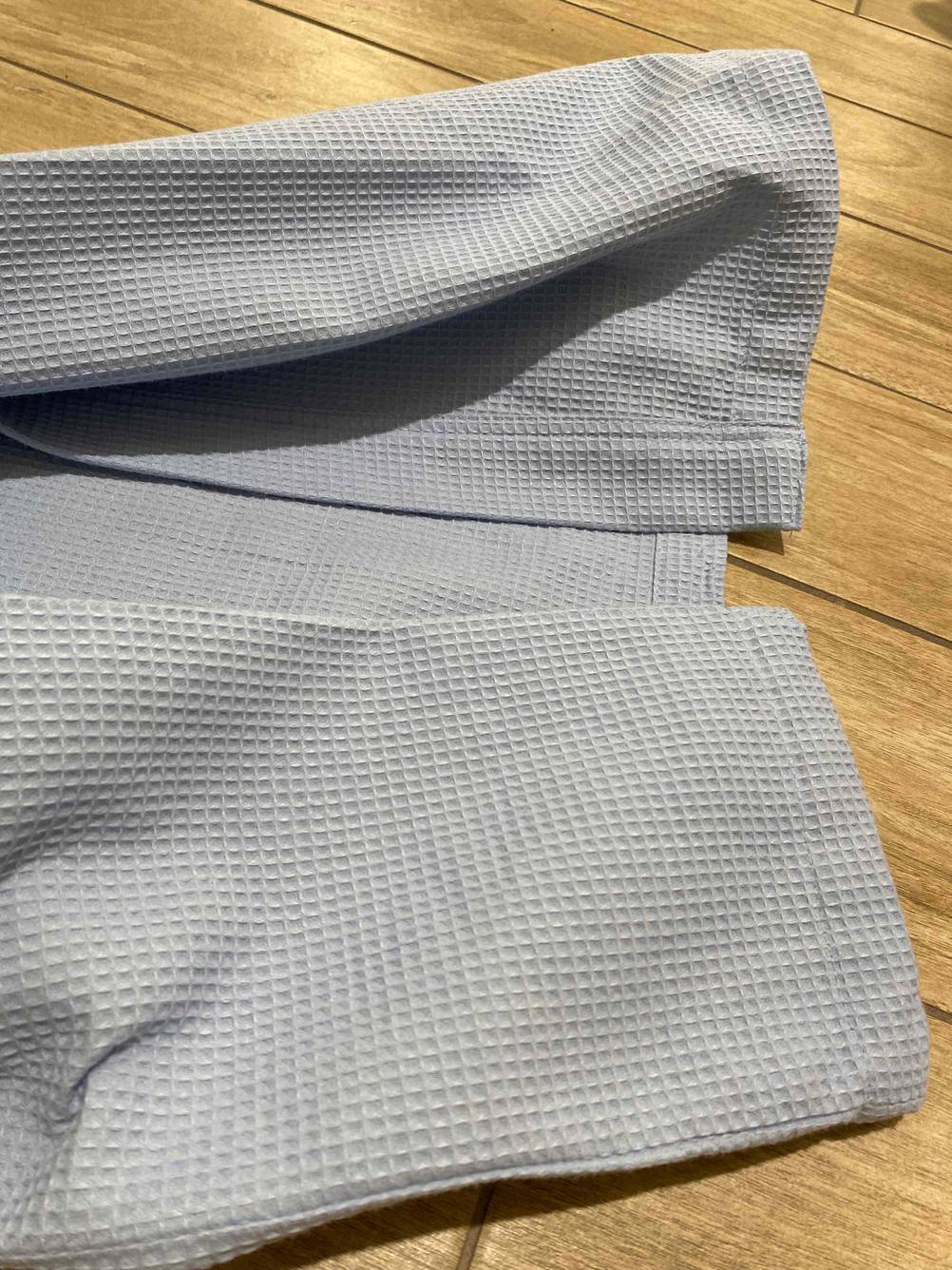 Nahaufnahme der Abschlusskante eines Bademantel Unisex im Test auf einem Holzboden.
