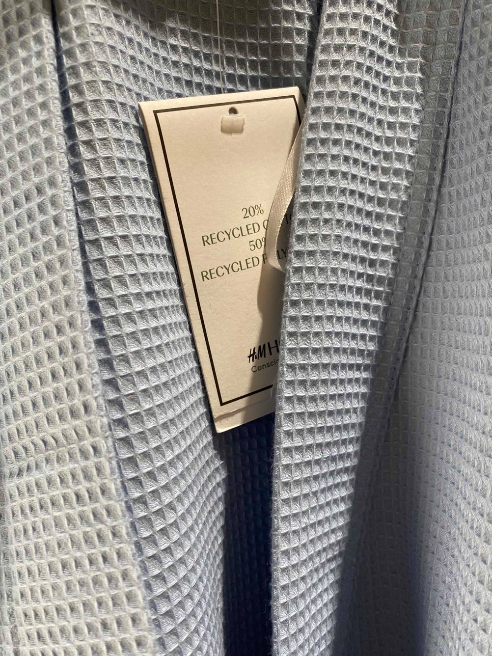 Nahaufnahme des Papier-Labels an einem getesteten Bademantel Unisex mit Informationen.