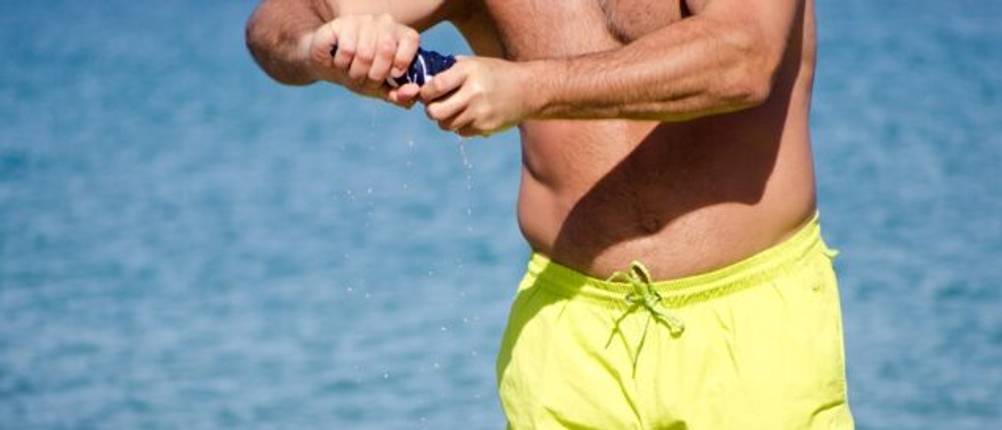 Mann am Strand will eine Badehose auswringen.