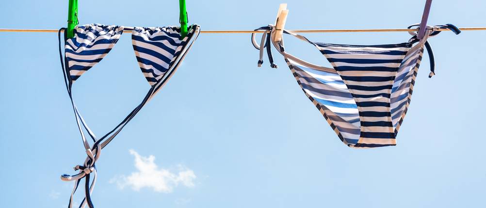 Ein Bikini hängt an einer Wäscheleine in der Sonne.