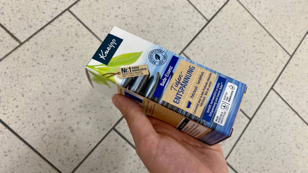 Eine Hand hält eine Packung des getesteten Badeöls leicht seitlich.