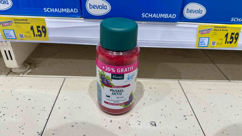 Vor einem Verkaufsregal steht eine Dose des getesteten Badesalzes auf dem Boden.