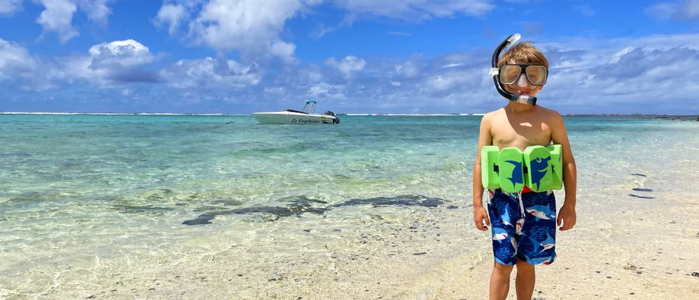 Badeschuhe für Erwachsene im Test: Kind mit Taucherbrille, Schnorchel, Schwimmhilfe und Badeschuhen am Strand