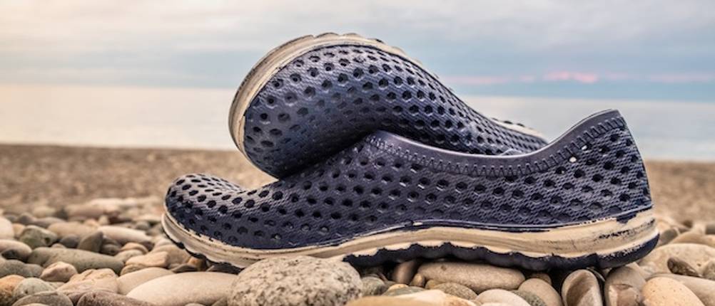 Blaue Kinder-Badeschuhe mit weißer Sohle auf Kieselsteinen getestet.