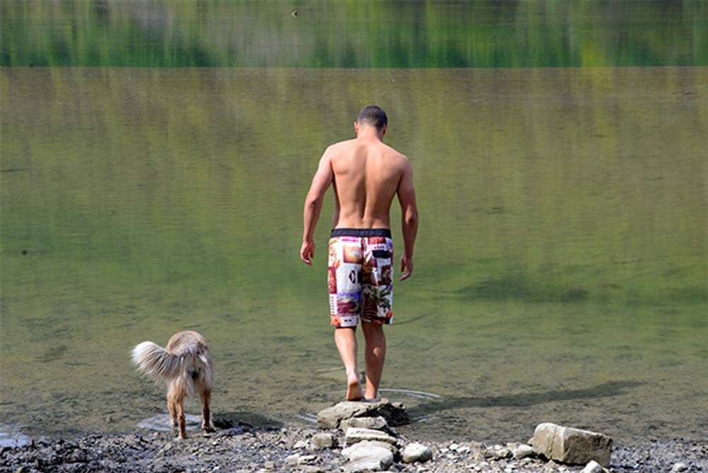 Herren-Badeshorts im Test: Ein Mann in Badeshorts mit seinem Hund am See.