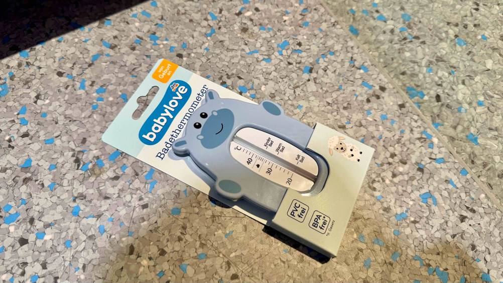 Auf einem blau-grauen Boden liegt ein Badethermometer Baby im Test in der Originalverpackung.
