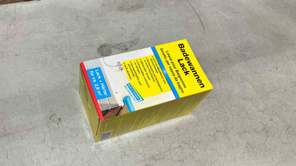 Eine Packung des getesteten Badewannenlacks liegt leicht seitlich auf einem Betonboden.
