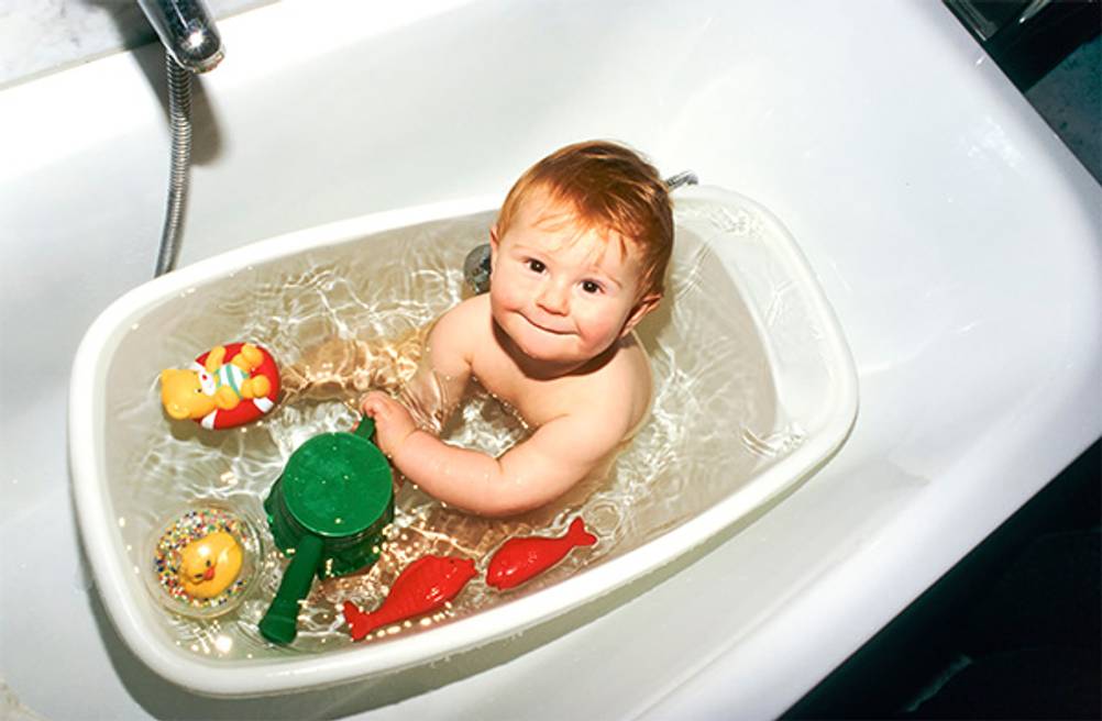 Badewannenspielzeug im Test: Ein Baby in einer kleinen Wanne mit viel Spielzeug.