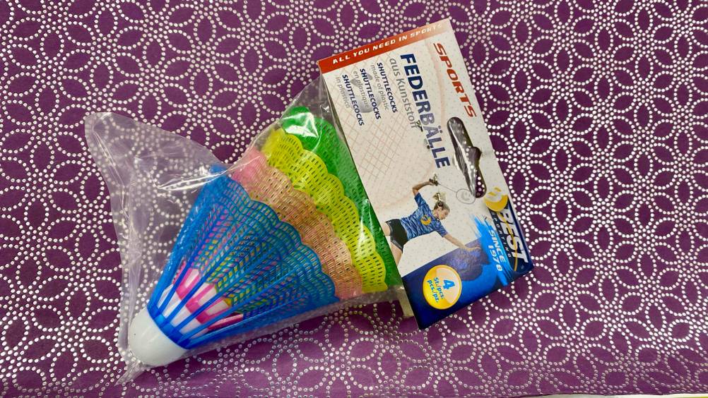 Eine transparente Packung der getesteten Badminton-Bälle auf einer gemusterten Tischdecke.