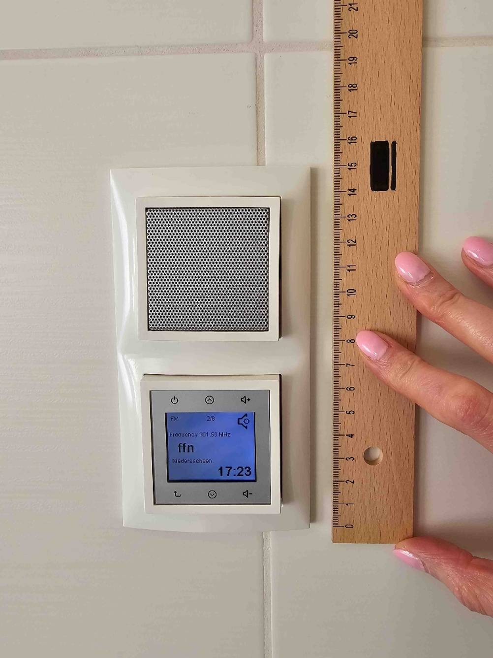 Getestet: Ein Badradio an der Wand, eine Hand hält ein Lineal an die rechte Seite.