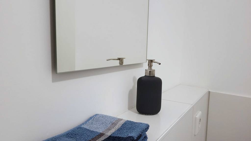 Badespiegel im Badezimmer mit Handtuch und Seifenspender. 