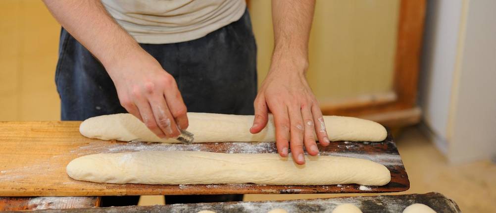 Bäckermesser-Test: Ein Bäcker ritzt mit einer Rasierklinge Schnitte in ein Baguette.
