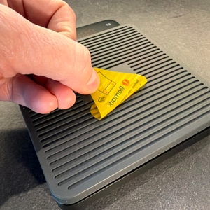 Eine Hand zieht eine Folie von der Bagail-Kaffeewaage