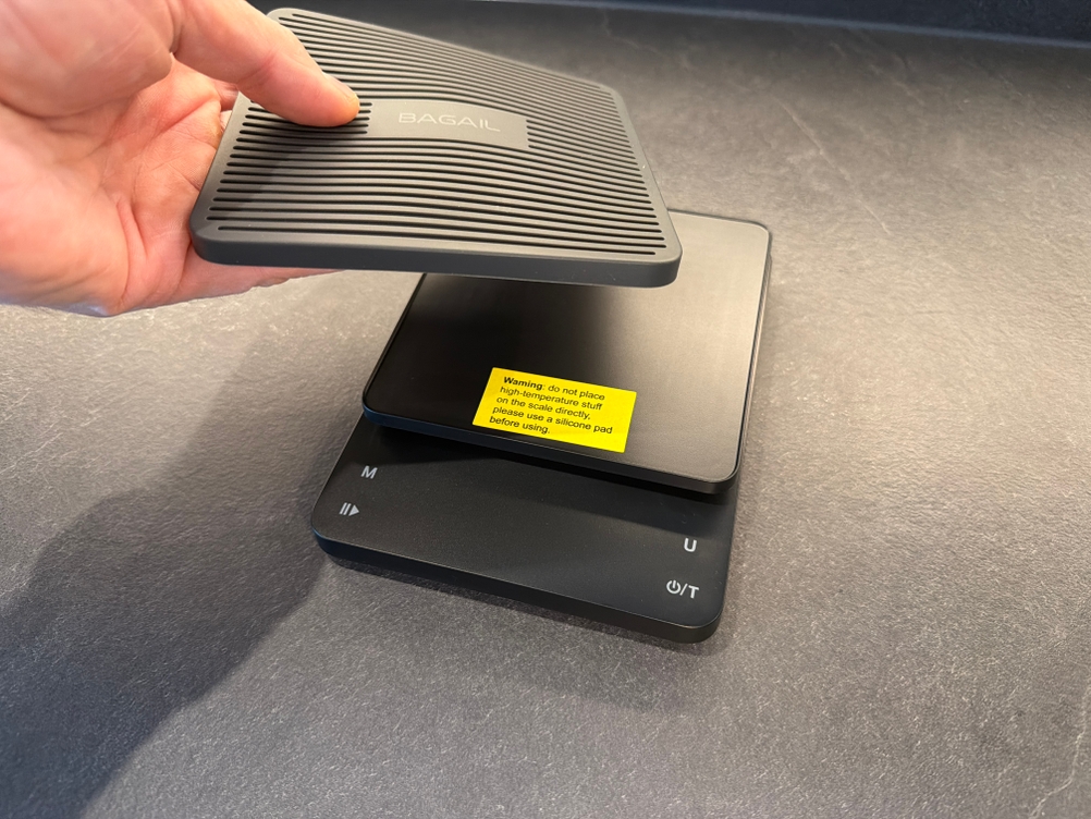 Eine Hand entfernt die Silikoneinlage von der Bagail-Kaffeewaage