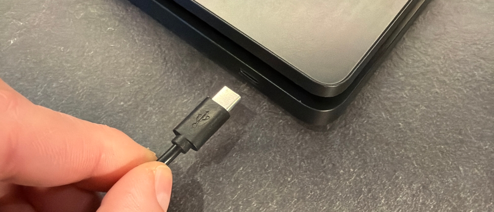 Eine Hand steckt ein Ladekabel in die Bagail-Kaffeewaage