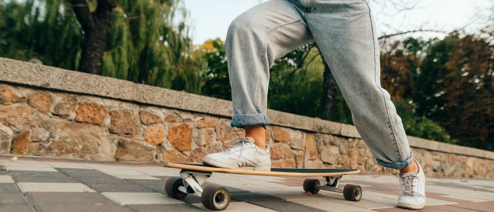 Junge Frau auf einem Skateboard testet Baggy-Jeans unter realen Bedingungen.