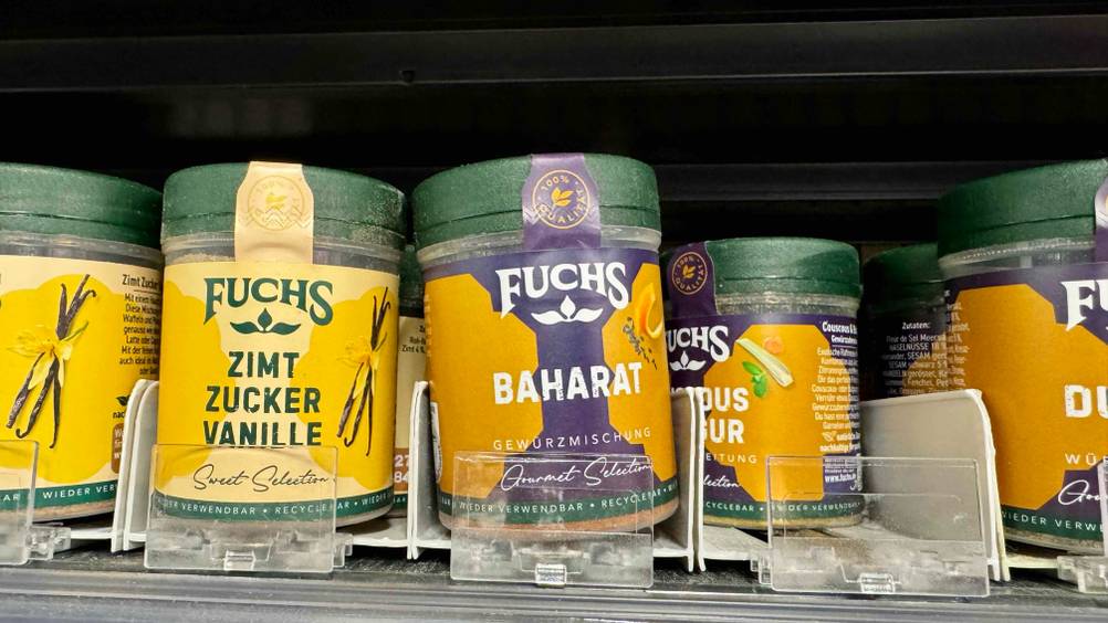 Mehrere Gläser des getesteten Baharats stehen in einem Verkaufsregal neben anderen Produkten.