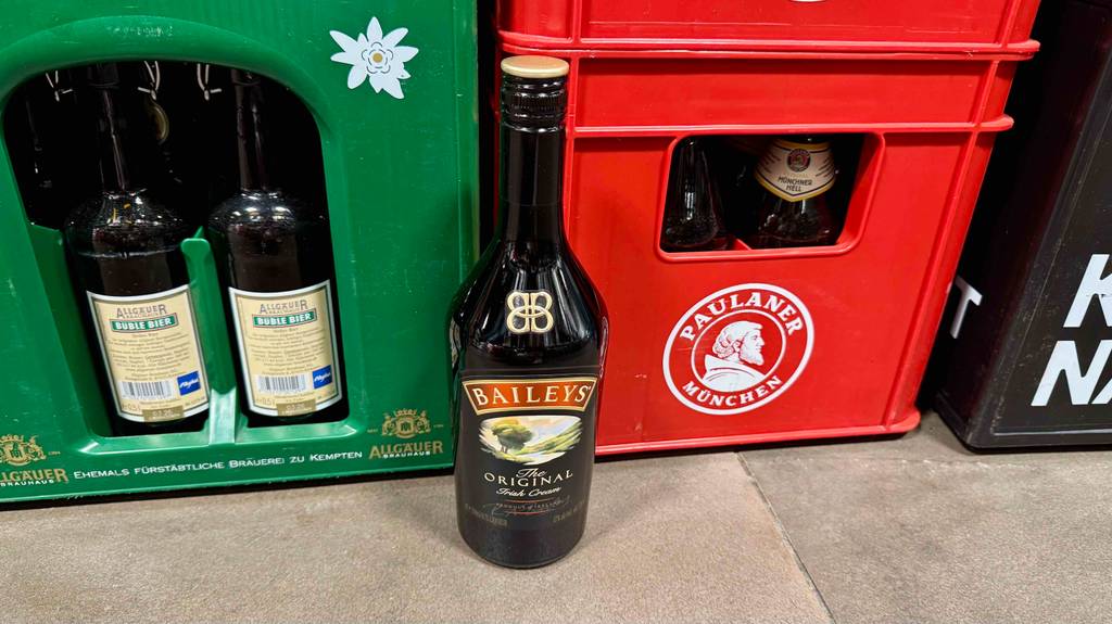 Eine Flasche getesteter Baileys steht vor Bierkisten.