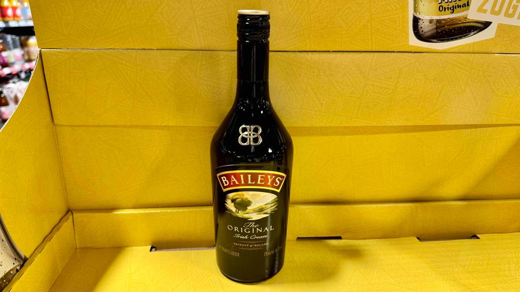 Eine Flasche Baileys steht zum testen in einem gelben Pappregalfach.