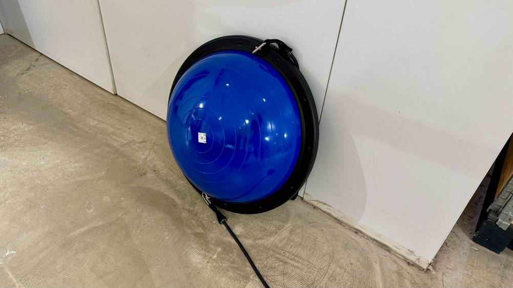 Ein getesteter Balance-Ball lehnt an einer hellen Wand.
