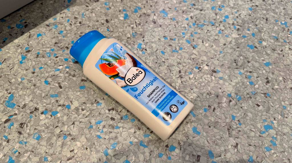 Eine Quetschflasche inklusive getestetem Feuchtigkeitsshampoo ohne Silikone liegt auf einem Linoleumbelag.