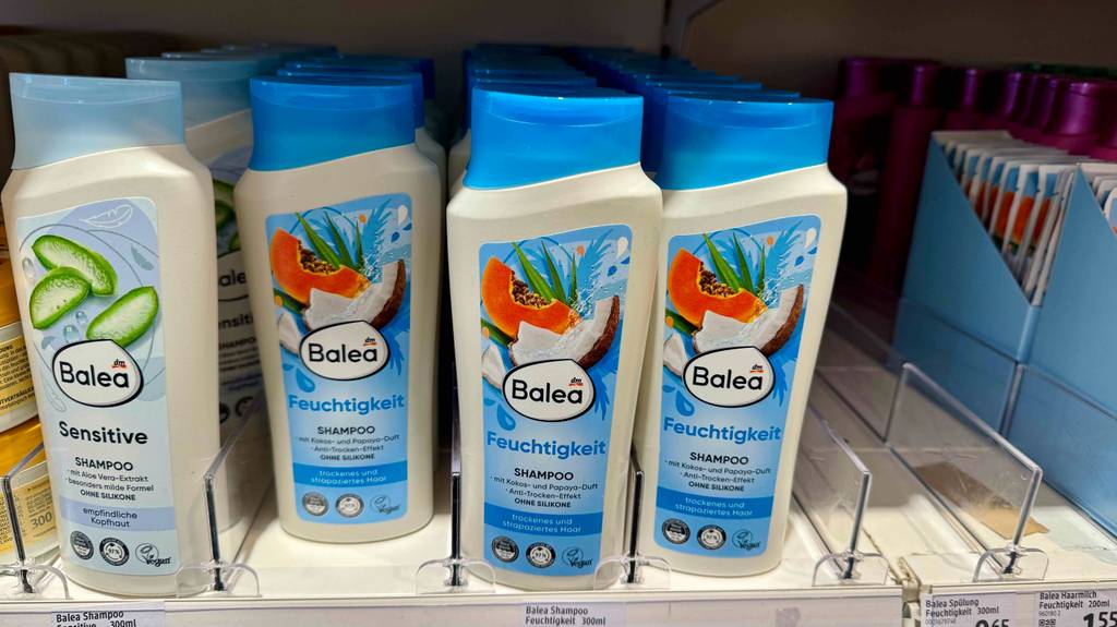Mehrere Quetschflaschen mit Feuchtigkeitsshampoo ohne Silikone im Test stehen in einem Verkaufsregal neben anderen Shampoosorten.