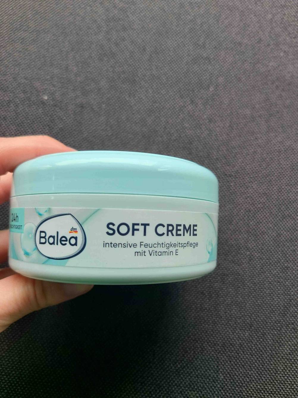 Eine Hand hält die Dose der getesteten Balea-Gesichtscreme seitlich vor eine dunkle Fläche.
