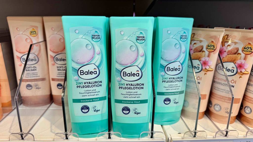 Hyaluron-Bodylotion im Test: Mehrere Flaschen stehen neben- und hintereinander zwischen anderen Produkten in einem Regal.