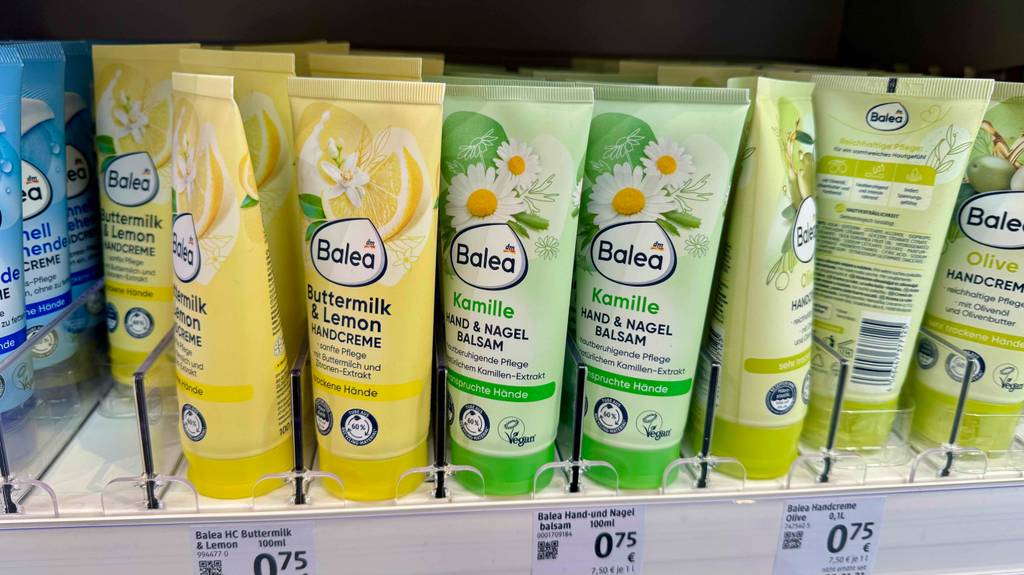 Mehrere Tuben mit Kamill-Handcremes im Test stehen in einem Regal im Drogeriemarkt.