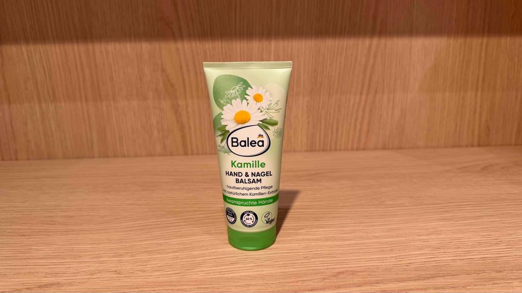 Getestet: Eine Kamill-Handcreme in der grünen Tube von Balea steht auf einem Regal in Holzoptik.