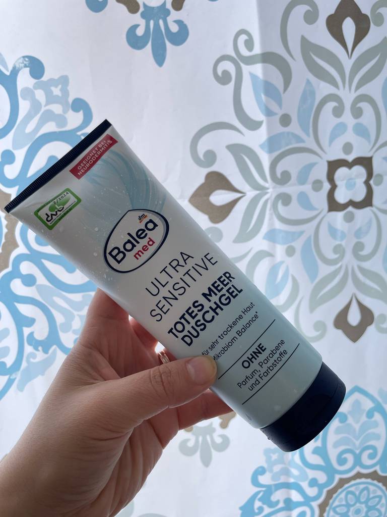 Im Test: Eine Hand hält eine Tube Duschgel für Neurodermitis.