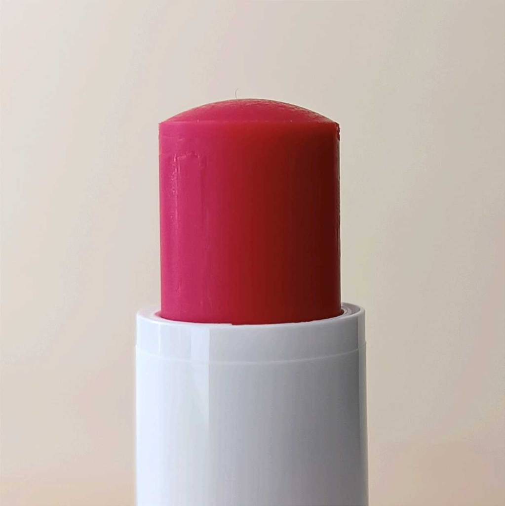 Roter Lippenpflegestift im Test geöffnet vor weißem Hintergrund.