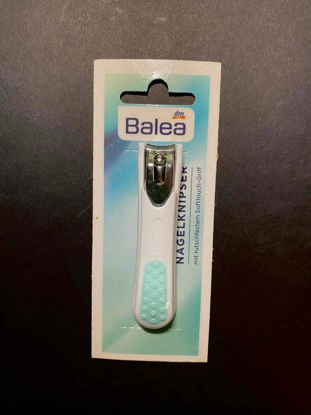 Ein original verpackter Nagelknipser der Marke Balea liegt zum testen auf einer dunklen Fläche.