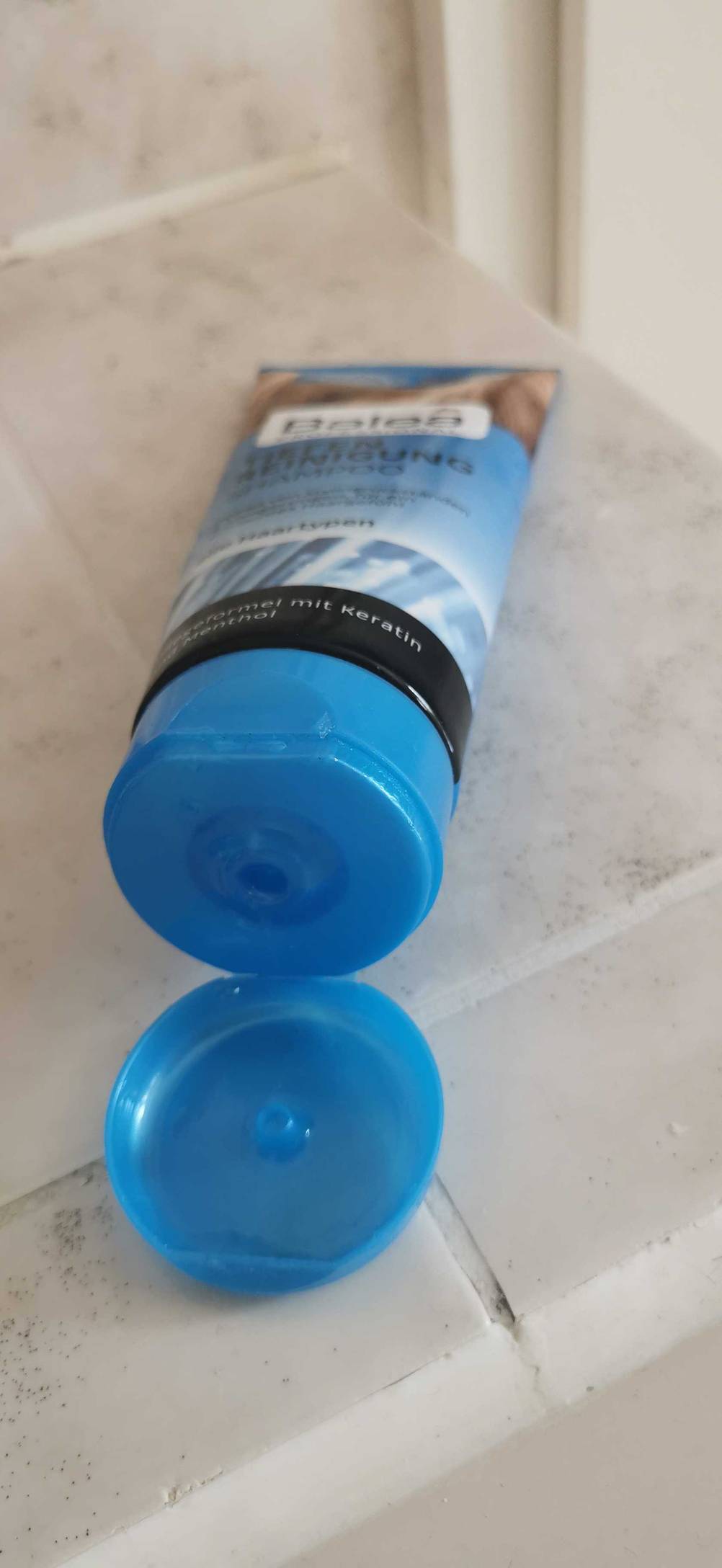 Nahaufnahme der geöffneten Verschlusskappe eines Tiefenreinigungsshampoos von vorne auf einer hellen Fläche.