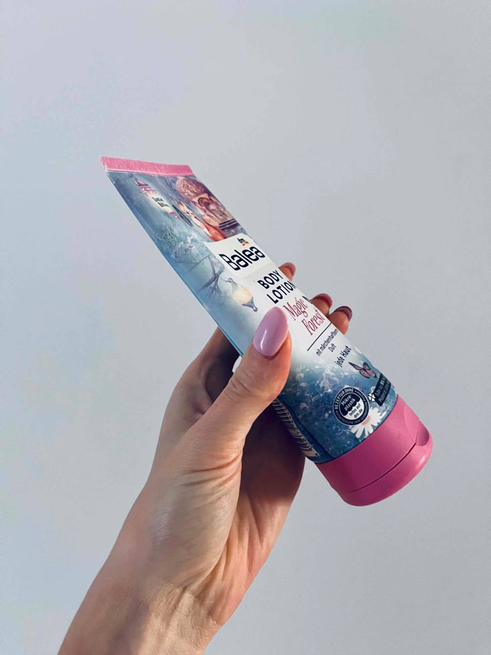 Bodylotion getestet: Eine Hand hält eine Tube seitlich vor eine hellen Wand.