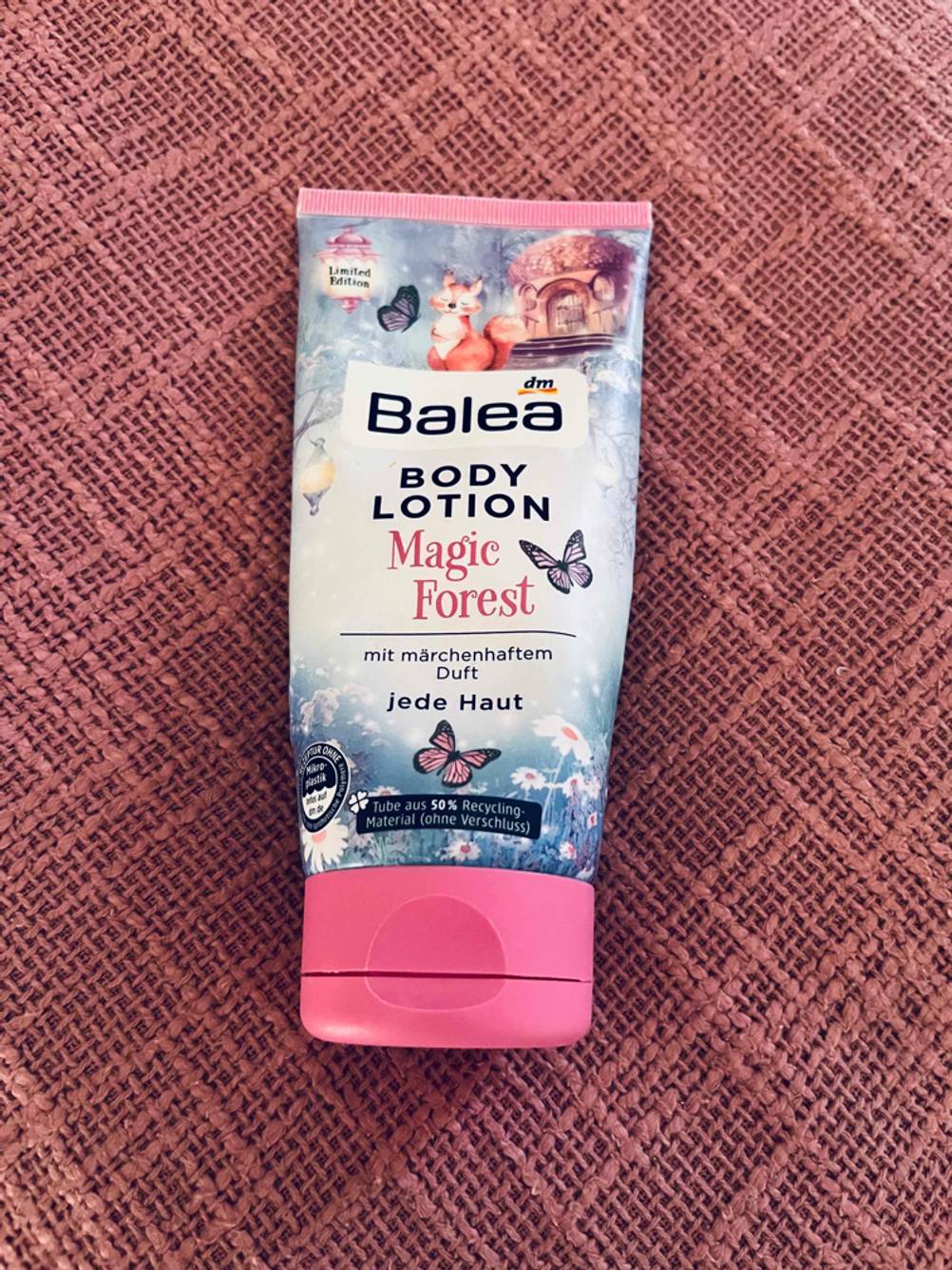 Auf einer rosa Fläche liegt eine Bodylotion im Test.