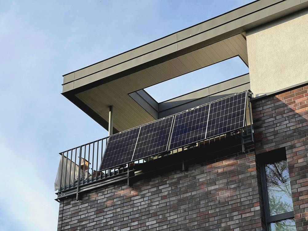 Hoymiles-Wechselrichter-Test: Am Balkongeländer eines modernen Wohnhauses ist ein Balkonkraftwerk befestigt.