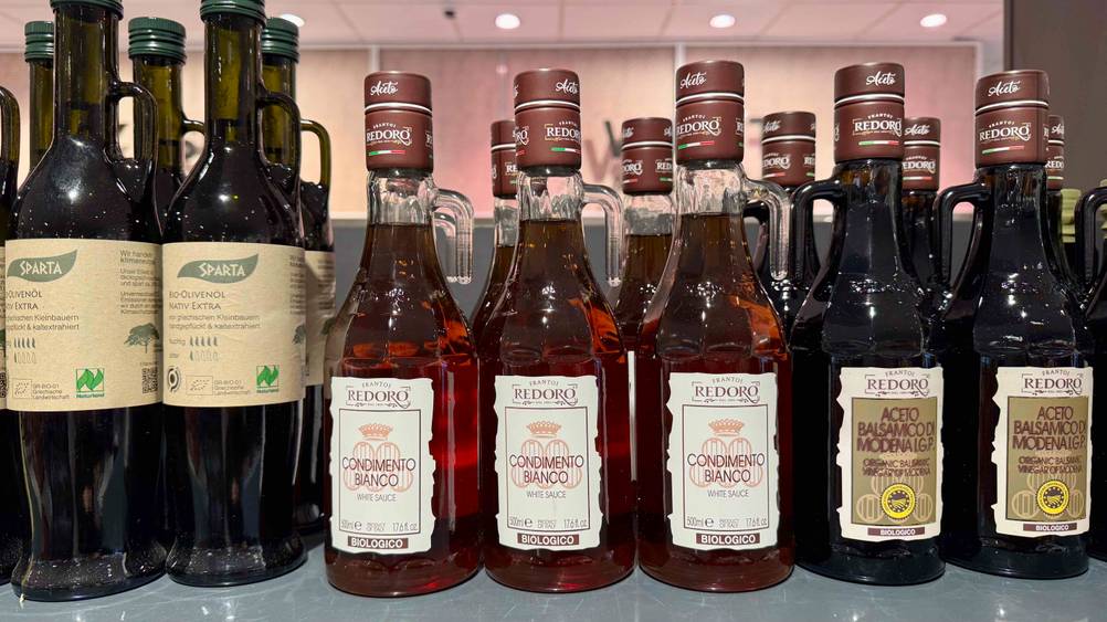 Mehrere Flaschen des getesteten Balsamico bianco stehen neben anderen Produkten in einem Verkaufsregal.