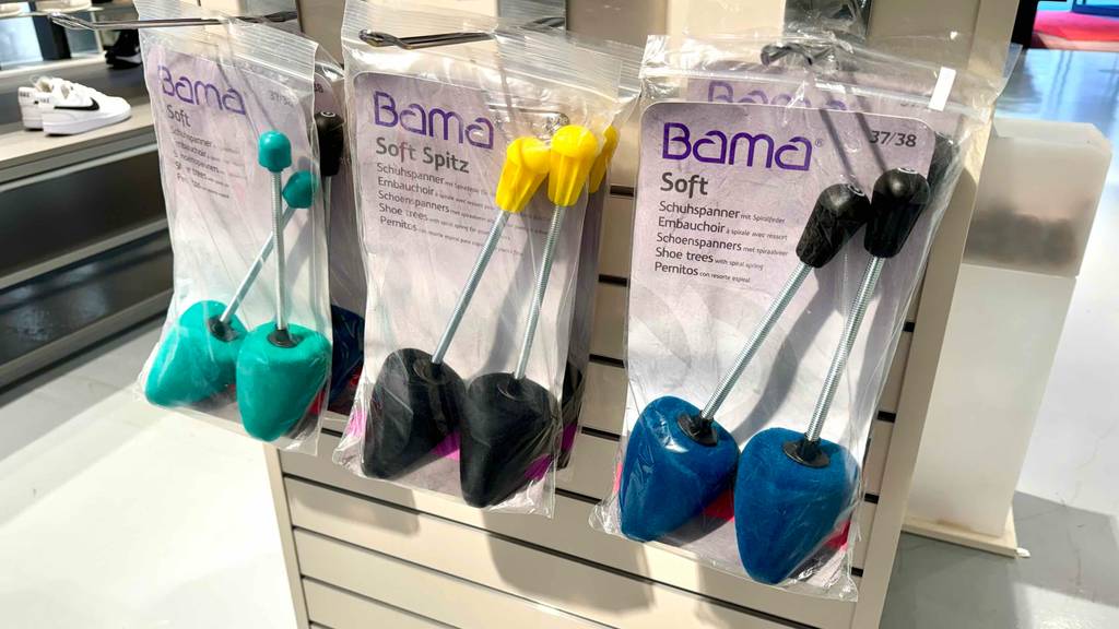 Mehrere verschiedenfarbige Schuhdehner hängen zum Testen neben- und hintereinander in einem Regal.